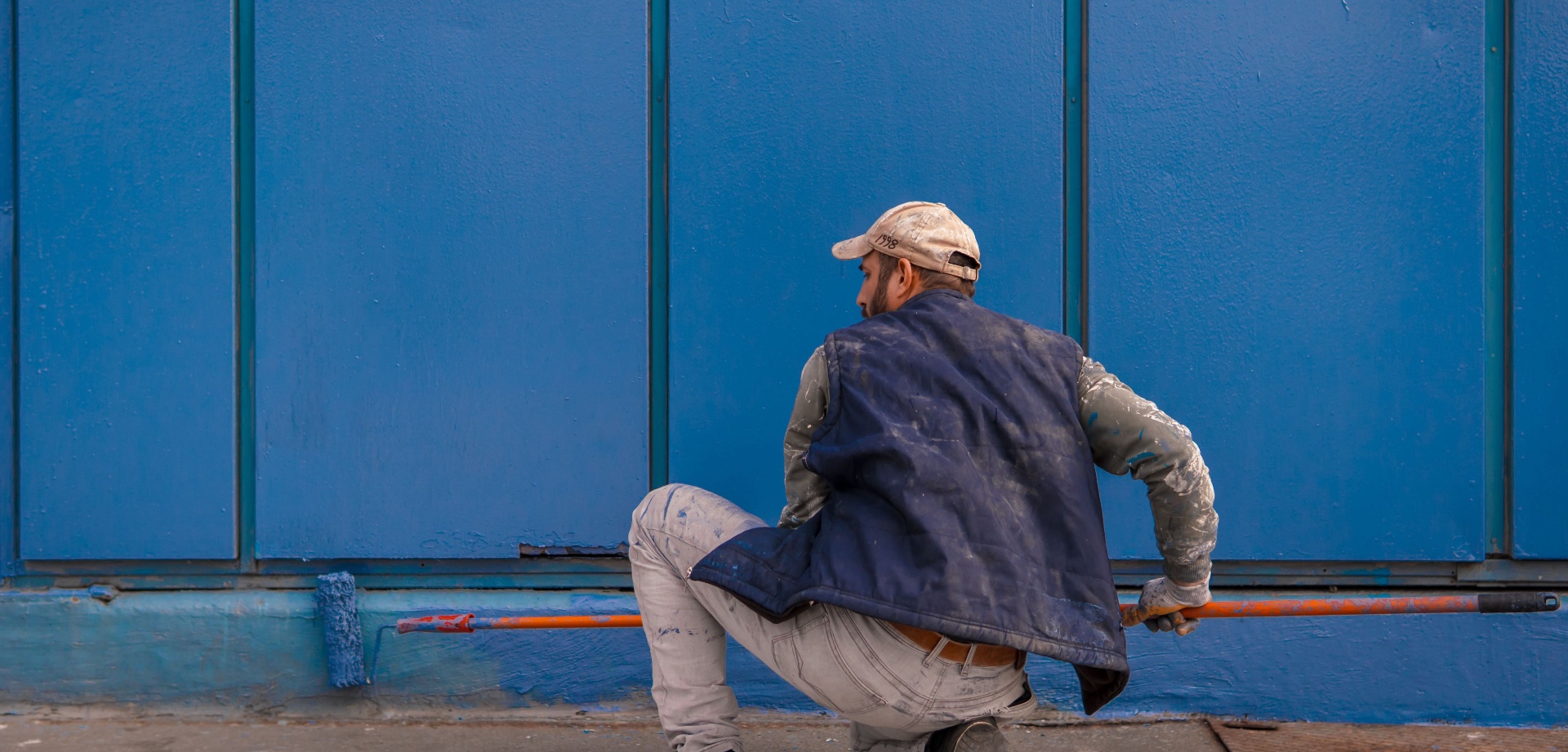 Professional painter rolling fresh blue paint on an exterior wall